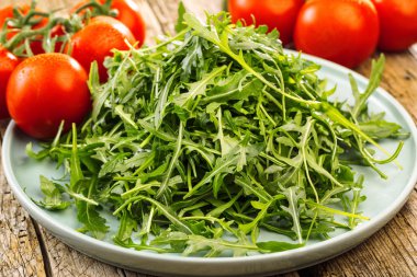 Taze roka ahşap kase, rucola bırakır. Roka rucola ahşap eski arka plan üzerinde.