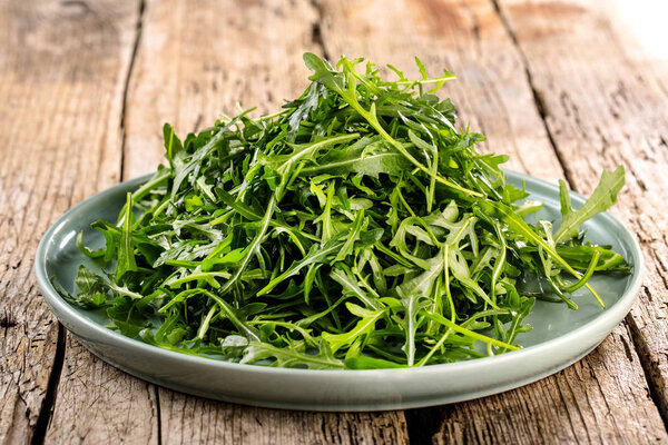 Fresh arugula leaves on wooden bowl, rucola. Arugula rucola on wooden old background.