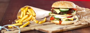 Fast food hamburger ve kızarmış patates ahşap arka plan üzerinde