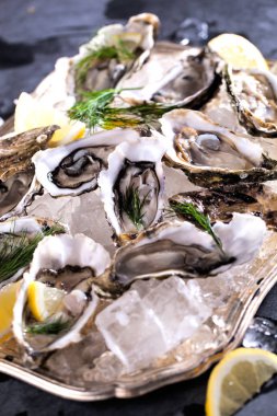 Dilimlenmiş limonla taze açılmış istiridye ezilmiş buzun üstünde fotokopi alanı ile sunuluyor.