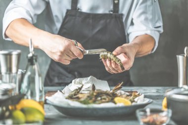 Şef ile koyu arka plan üzerinde kaplan karides pişirme 