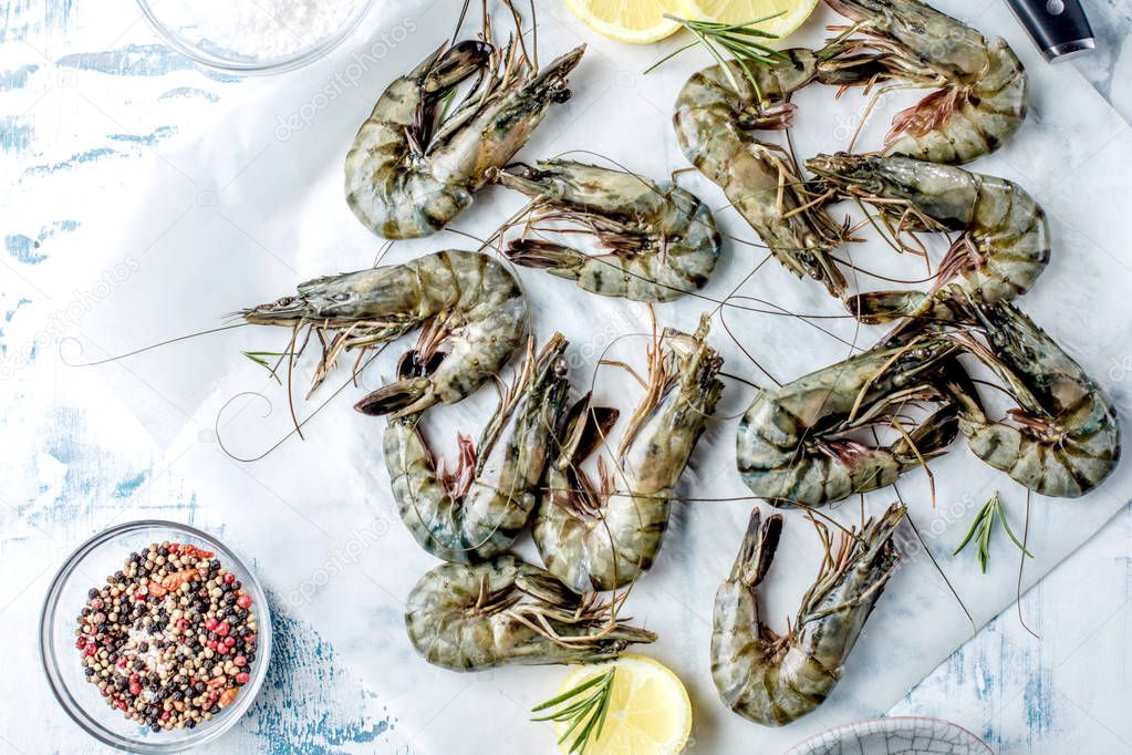 fresh shrimps or prawns raw on kitchen table board with ingredients
