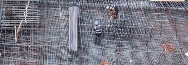 İnşaat işçileri inşaat alanında çelik takviye çubuğu üretiyorlar.