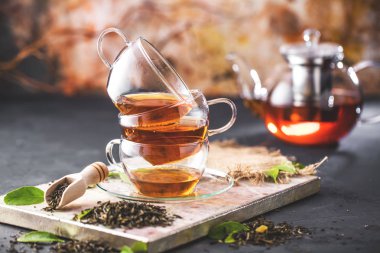 Taze demlendi siyah çay, sıcak yumuşak ışık, koyu arka plan.