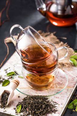 Taze demlendi siyah çay, sıcak yumuşak ışık, koyu arka plan.