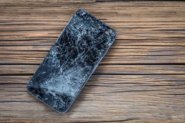 ahşap arka plan üzerinde kırık dokunmatik ekrana sahip cep telefonu.