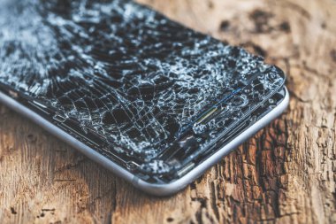 ahşap arka plan üzerinde kırık dokunmatik ekrana sahip cep telefonu.