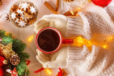 Kupa holding eldivenli eller sıcak içecek ile dolu.