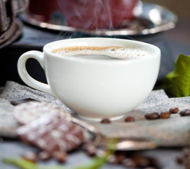 kahve fincanı ve masada kahve çekirdekleri