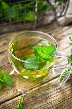 Bir fincan sıcak çay, kamış şekeri, çay yaprakları ve nane bitkisi..