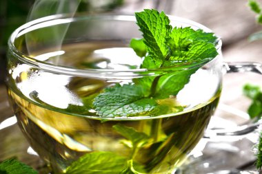 Bir fincan sıcak çay, kamış şekeri, çay yaprakları ve nane bitkisi..