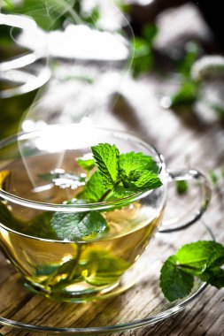 Bir fincan sıcak çay, kamış şekeri, çay yaprakları ve nane bitkisi..