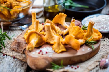 Sarı mantar Cantharellus cibarius karanlık mutfak masasının üzerinde orman bitkileri ile vintage plaka 