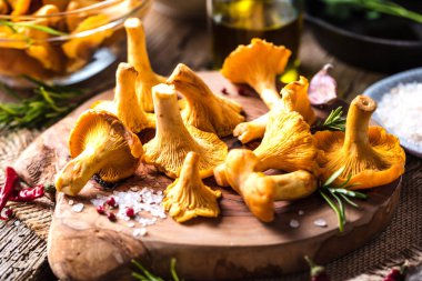 Sarı mantar Cantharellus cibarius karanlık mutfak masasının üzerinde orman bitkileri ile vintage plaka 