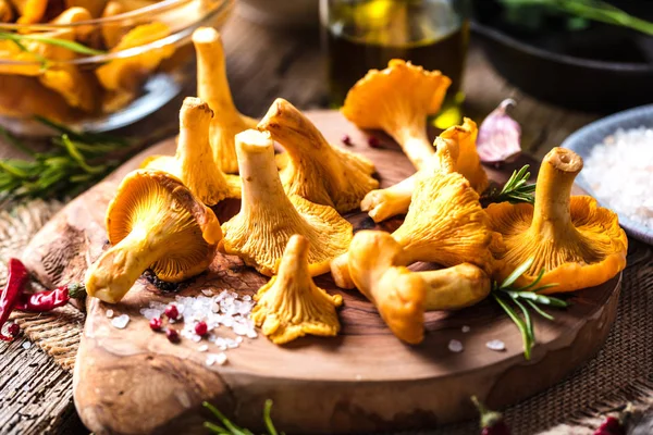 Yellow mushrooms chanterelle in vintage plate with forest plants on dark kitchen table