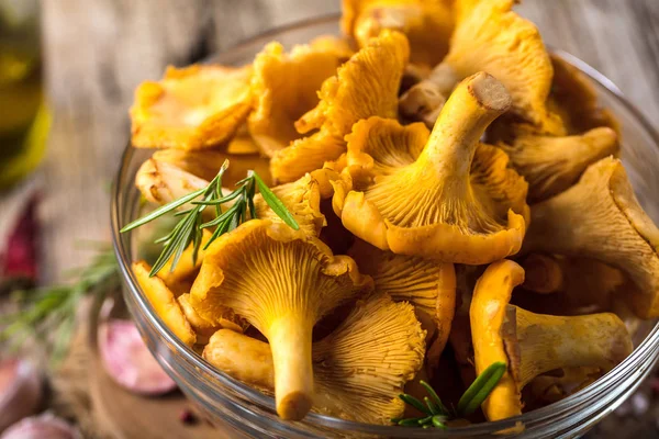 Yellow mushrooms chanterelle in vintage plate with forest plants on dark kitchen table