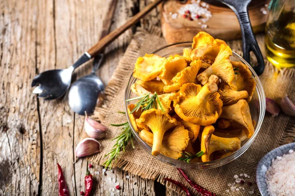 Yellow mushrooms chanterelle in vintage plate with forest plants on dark kitchen table