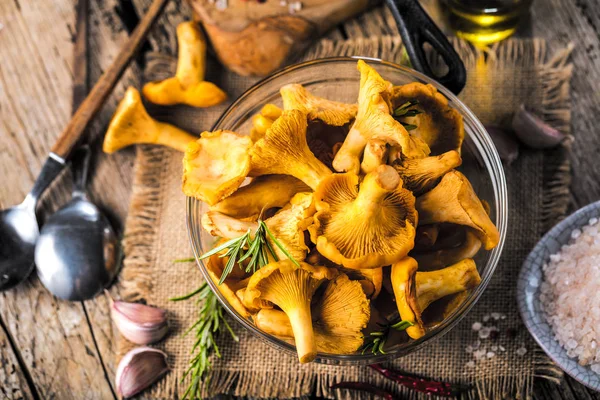 Yellow mushrooms chanterelle in vintage plate with forest plants on dark kitchen table