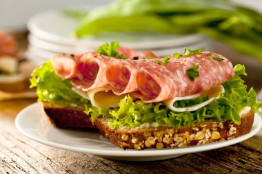 Baharatlı İtalyan salam sosis ve eski grunge rustik ahşap tahta üzerinde salata ile tepesinde tohumları ile kepekli ekmek