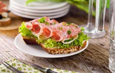 Baharatlı İtalyan salam sosis ve eski grunge rustik ahşap tahta üzerinde salata ile tepesinde tohumları ile kepekli ekmek