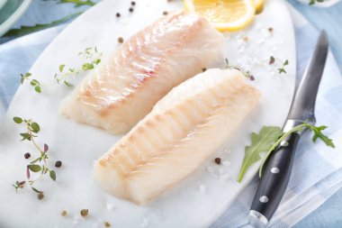 Taze balık, otlar ve limon eklenmesi ile ham morina fileto 