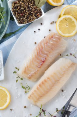 Taze balık, otlar ve limon eklenmesi ile ham morina fileto 