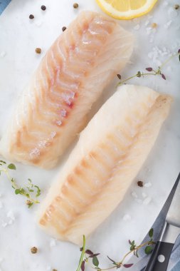 Taze balık, otlar ve limon eklenmesi ile ham morina fileto 