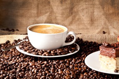 fincan kahve ve kek üzerine kahve çekirdekleri.