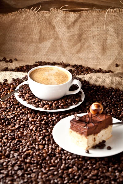 cup of coffee and  cake on coffee beans.