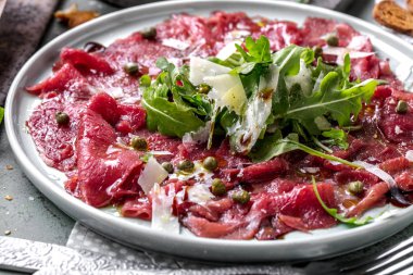 Dana carpaccio hardal ve parmesan ile siyah plaka üzerinde