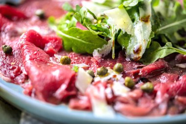 Dana carpaccio hardal ve parmesan ile siyah plaka üzerinde