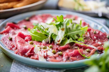 Dana carpaccio hardal ve parmesan ile siyah plaka üzerinde