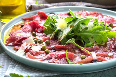 Dana carpaccio hardal ve parmesan ile siyah plaka üzerinde