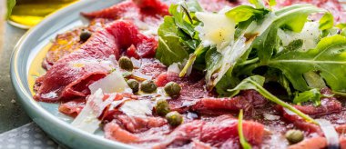 Dana carpaccio hardal ve parmesan ile siyah plaka üzerinde