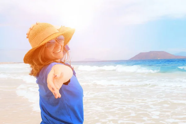 Happy traveller woman in blue dress enjoys her tropical beach vacation