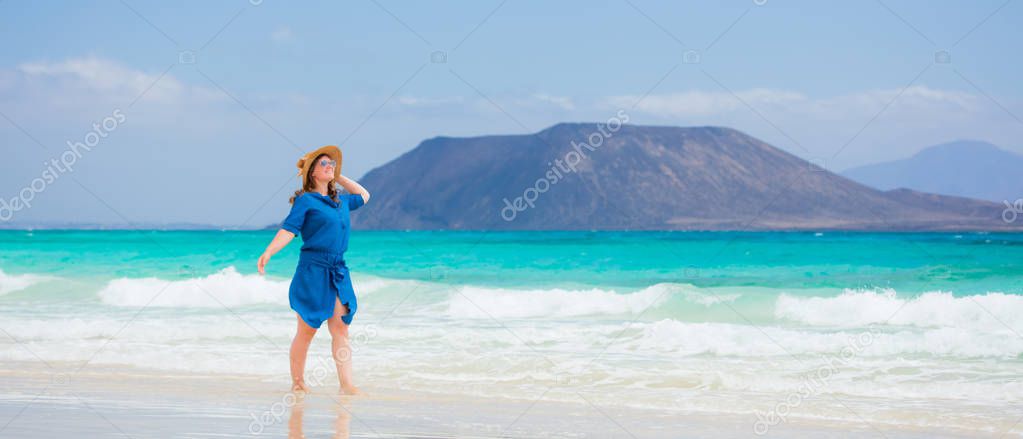 Happy traveller woman in blue dress enjoys her tropical beach vacation