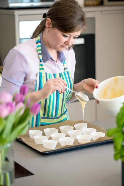 Charming woman baking in the kitchen at home blueberry muffins.