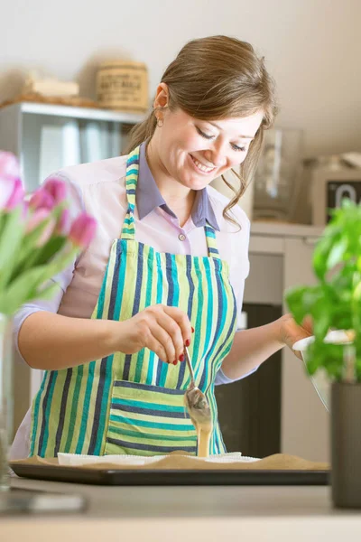 Charming woman baking in the kitchen at home blueberry muffins.