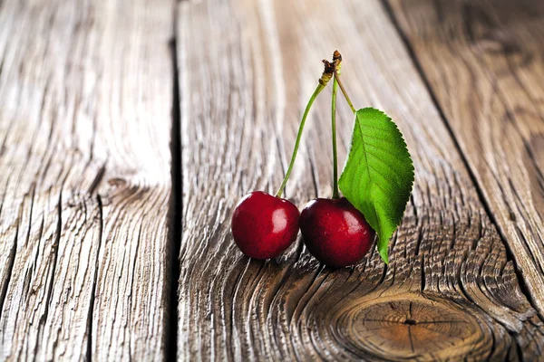 Cherries on wooden table with water drops macro background.