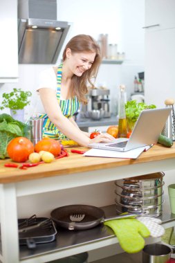 Mutfakta yemek hazırlarken bilgisayar arayan kadın yemek