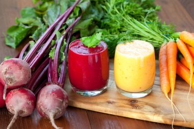 Ahşap arka plan üzerinde kırmızı pancar ve havuç suyu karıştırın