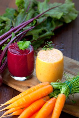 Ahşap arka plan üzerinde kırmızı pancar ve havuç suyu karıştırın