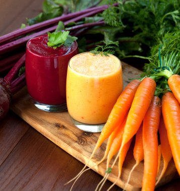 Ahşap arka plan üzerinde kırmızı pancar ve havuç suyu karıştırın