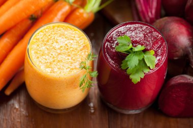 Ahşap arka plan üzerinde kırmızı pancar ve havuç suyu karıştırın