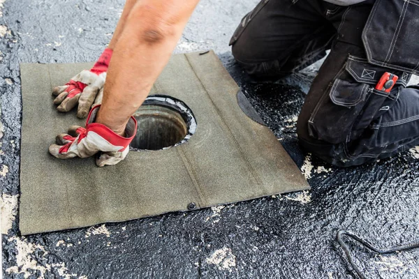 Flat roof installation. Heating and melting bitumen roofing felt.