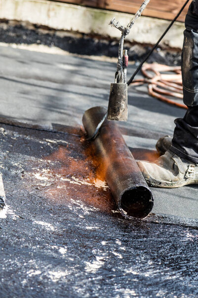 Установка кровли с пропановой горелкой во время строительных работ
