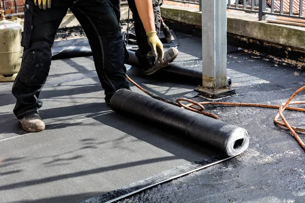 Flat roof installation. Heating and melting bitumen roofing felt.