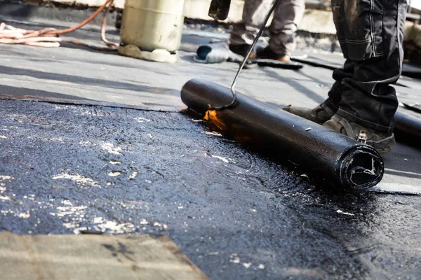 Flat roof installation. Heating and melting bitumen roofing felt.