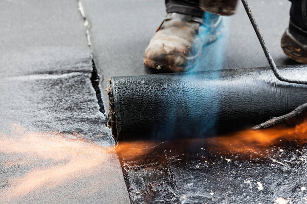 Установка кровли с пропановой горелкой во время строительных работ
