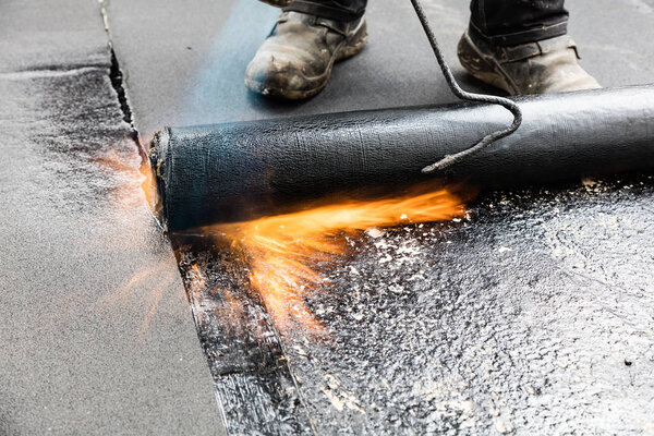 Установка кровли с пропановой горелкой во время строительных работ
